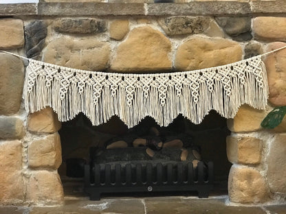 Macrame hanging above a stone fireplace with firewood inside