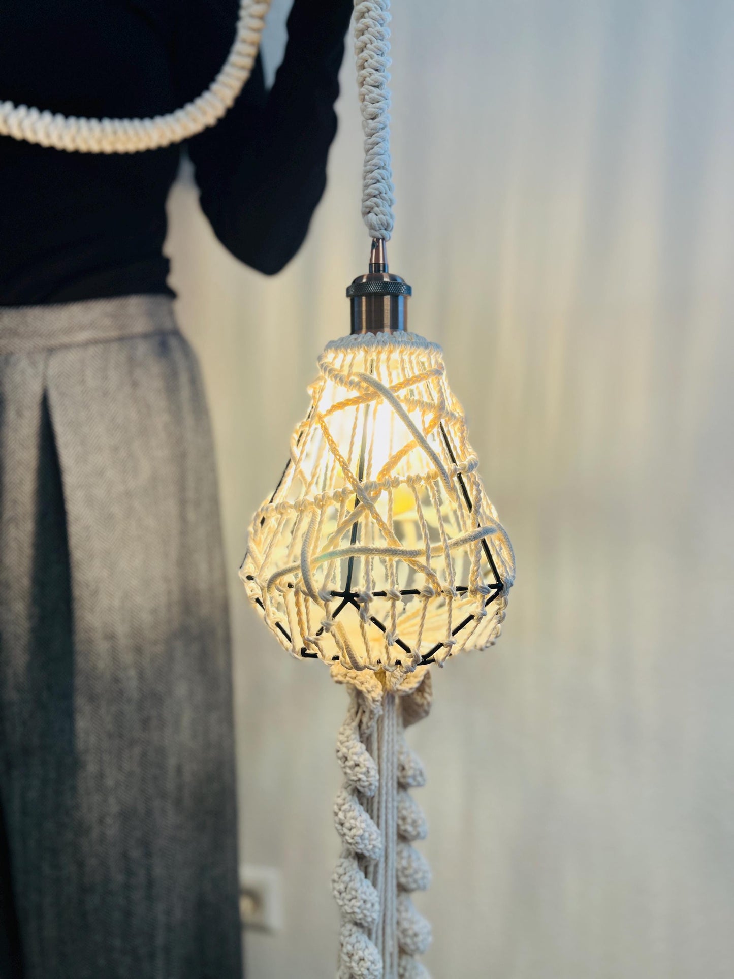 Decorative pendant light with woven design and braided cord, blurred background