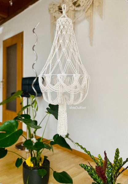Macrame chandelier hanging in a room with plants and a door in the background.