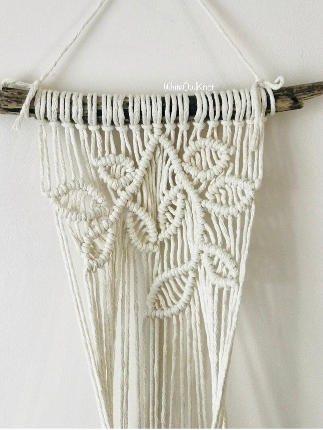 Macrame wall hanging with intricate patterns on a white background