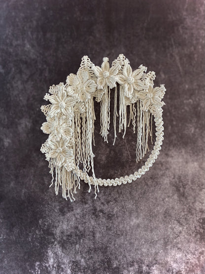 Decorative headpiece with floral designs and tassels on a textured dark background