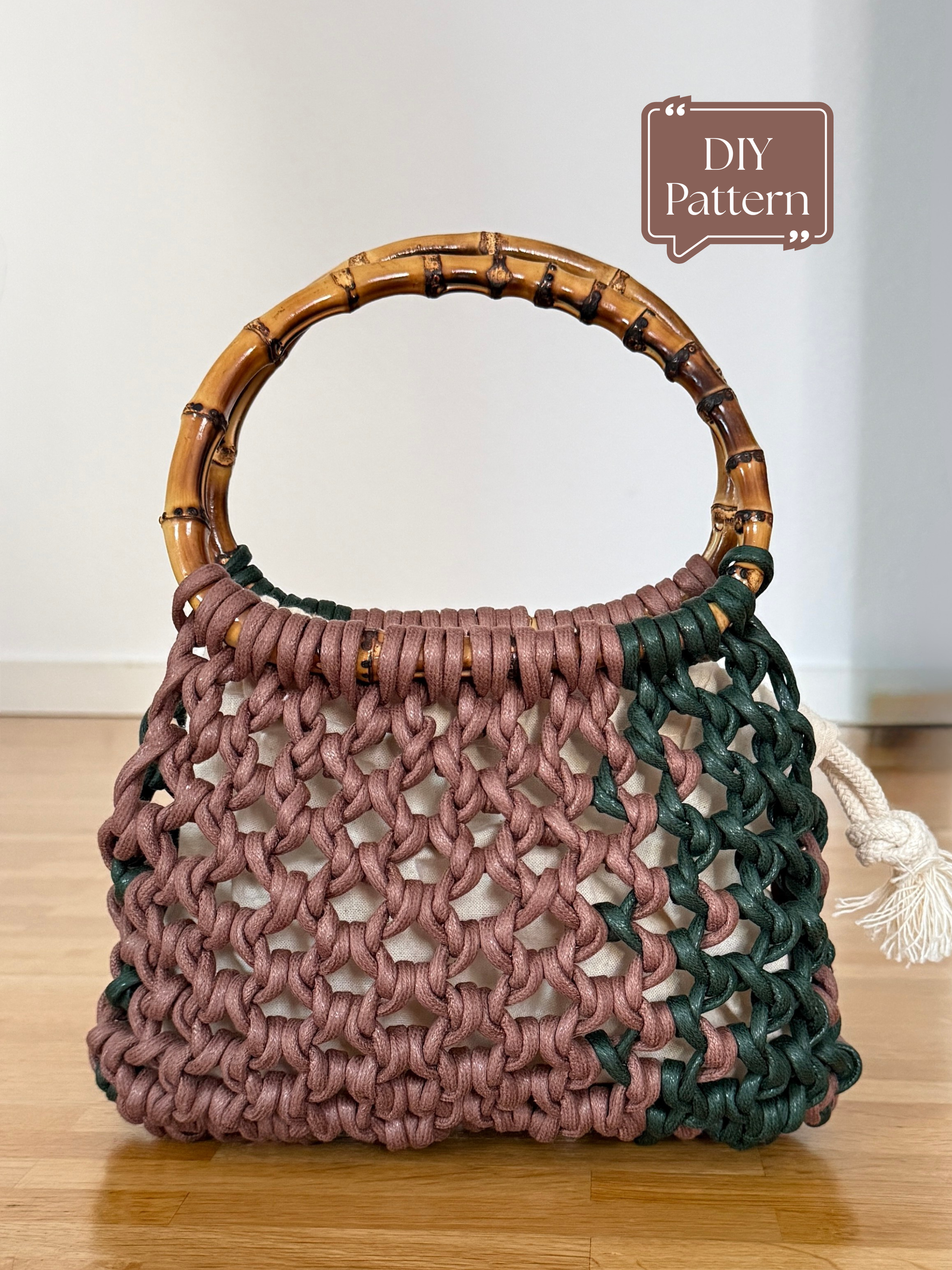Handmade macramé bag with an open woven knot pattern, made from cotton cords in muted pink and dark green tones, featuring round bamboo handles and a natural fabric lining; shown as a DIY macramé pattern example.
