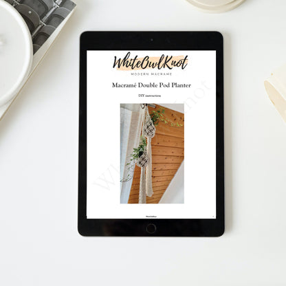 Tablet displaying a WhiteOwlKnot macrame double pod planter tutorial on a white surface.
