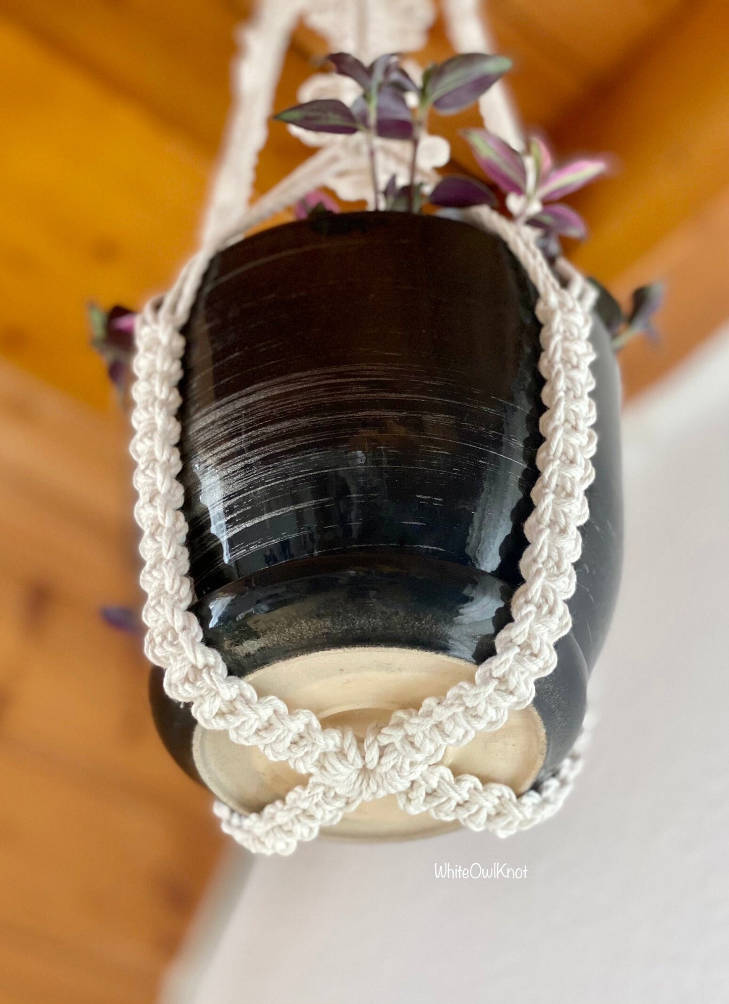 Decorative black vase with white crocheted lid on a wooden surface