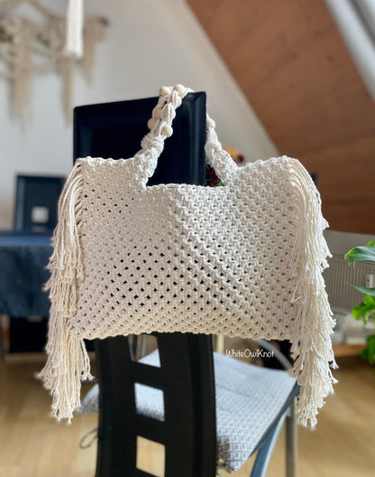 White macrame bag with fringe on a chair indoors