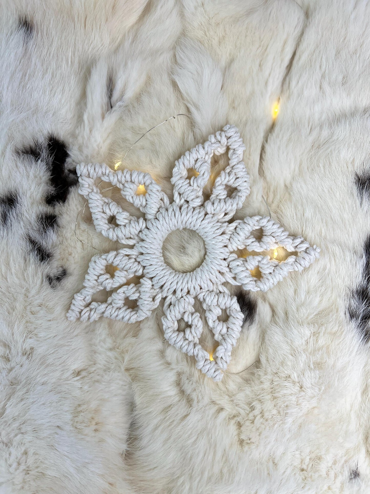 White macrame snowflake decoration on a textured white surface