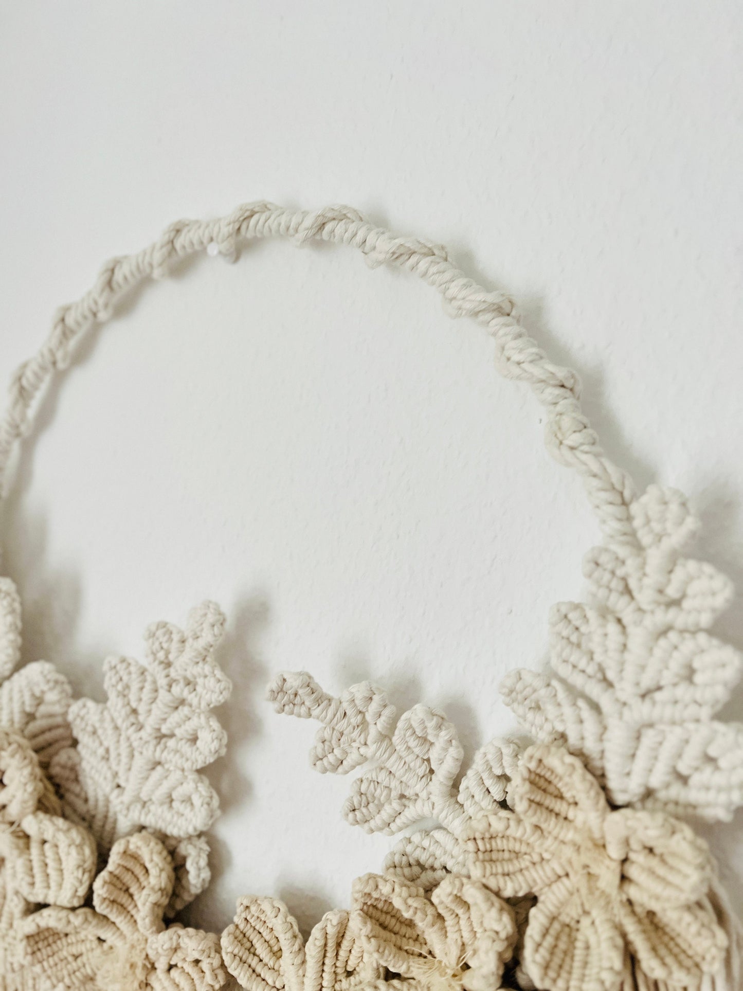 Macrame wall hanging with floral patterns on a plain background