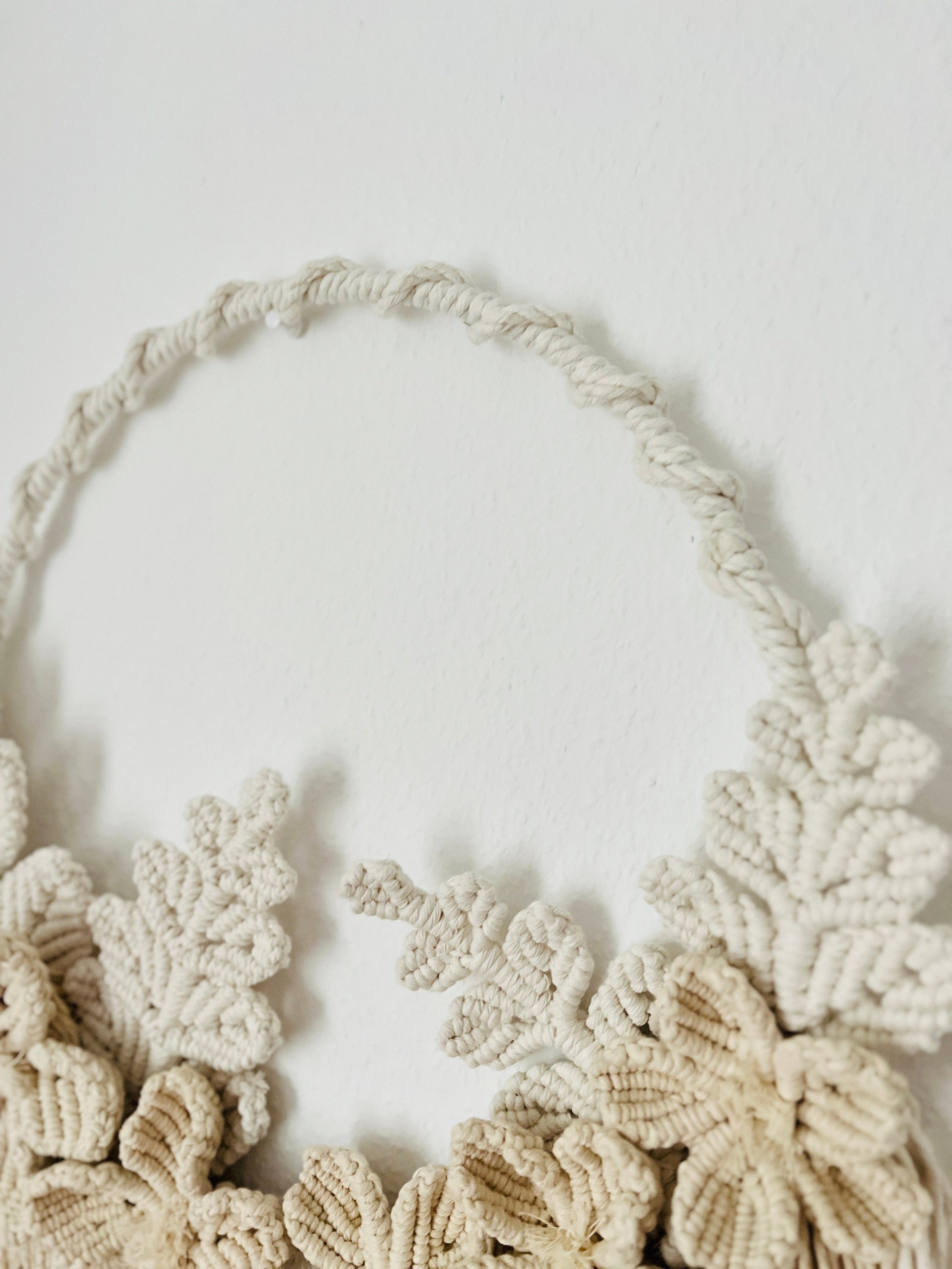 Macrame wall hanging with floral patterns on a plain background
