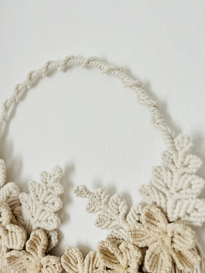 Macrame wall hanging with floral patterns on a plain background