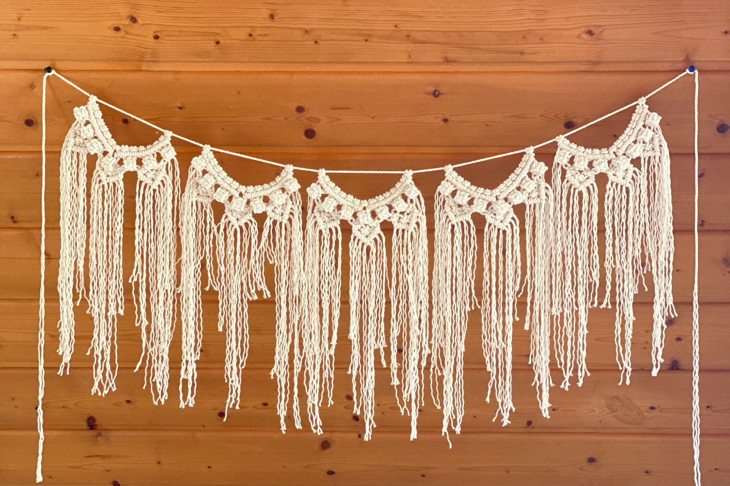 Crocheted fringe garland hanging against a wooden wall