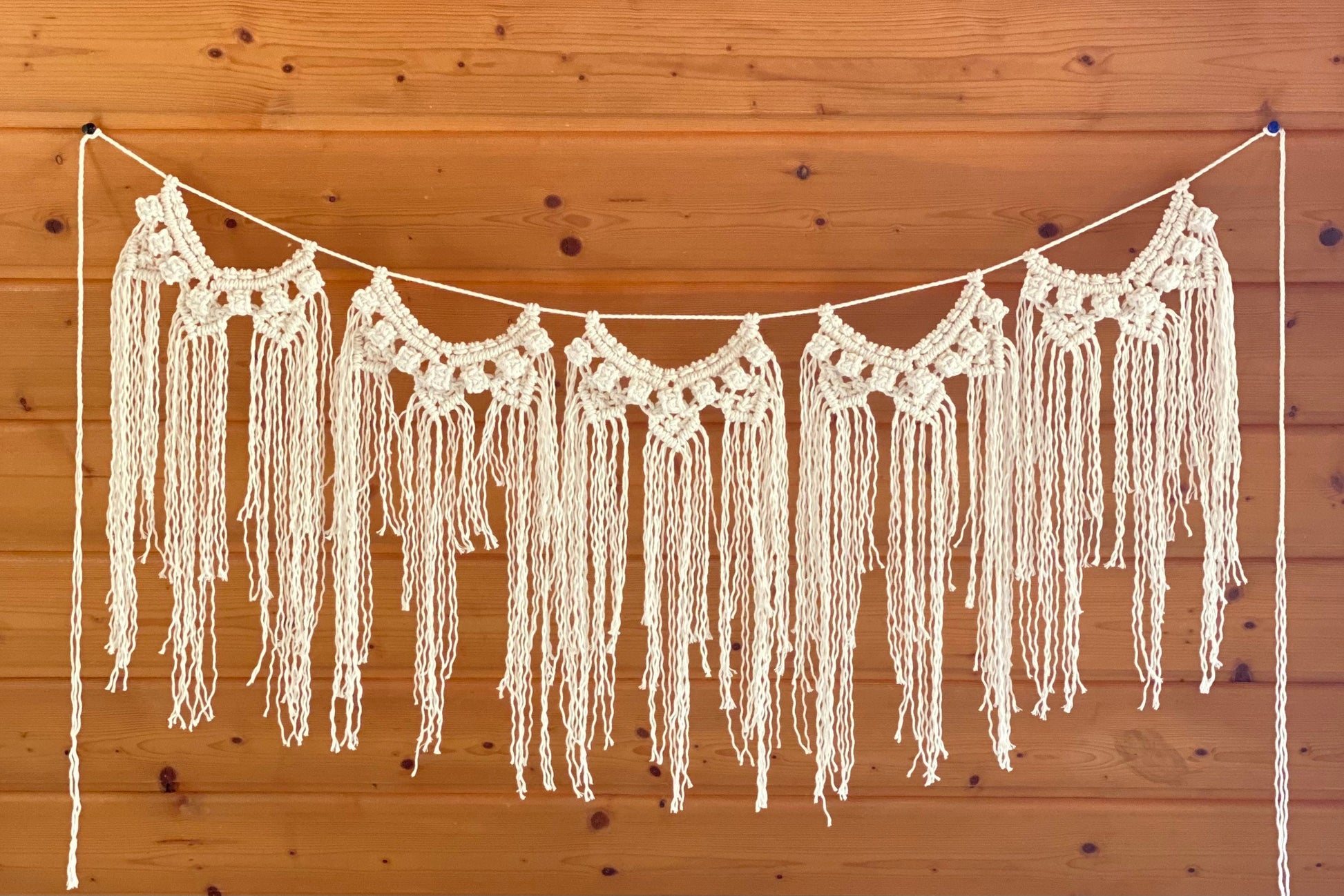 Crocheted fringe garland hanging against a wooden wall