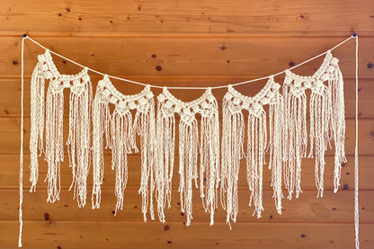 Crocheted fringe garland hanging against a wooden wall