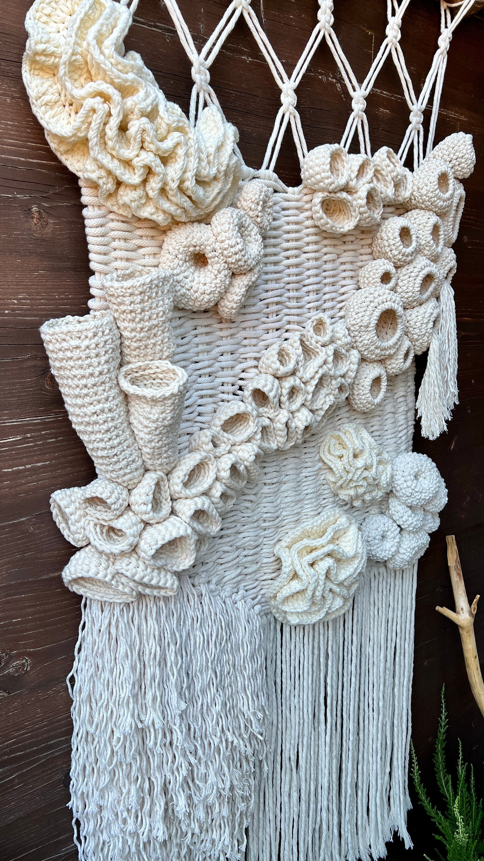 Macrame wall hanging with coral reef details and tassels on a wooden background