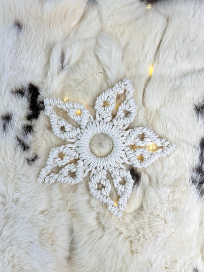 Decorative white snowflake ornament on a textured white surface