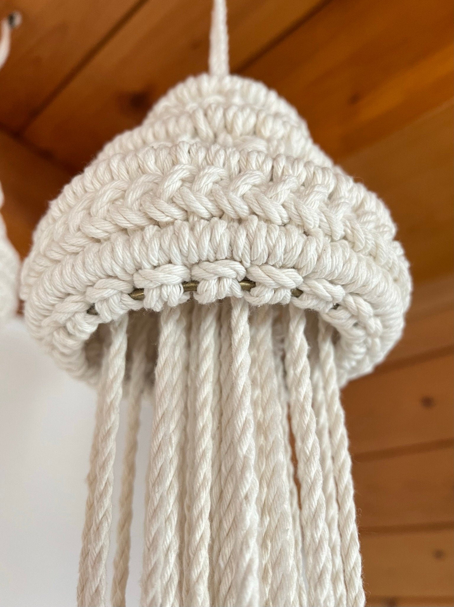 Beige woven jellyfish hanging against a wooden background