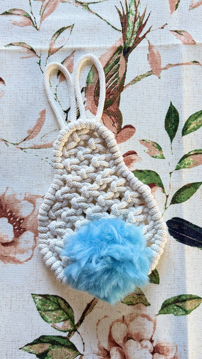 Macrame bunny with a blue pom-pom on a floral background