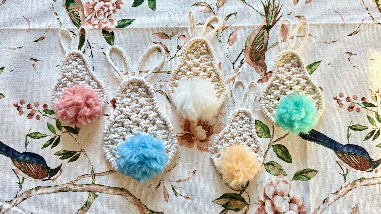Macrame easter bunnies with colorful pom-poms on a floral background