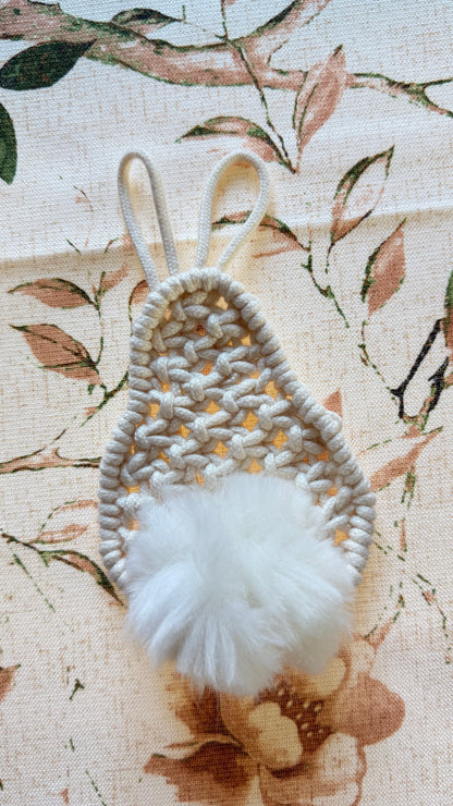 Handmade macrame bunny with a white pom-pom on a floral fabric background