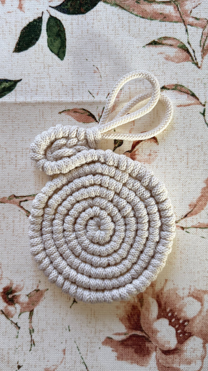 Round woven coaster with bunny ears on a floral-patterned fabric background