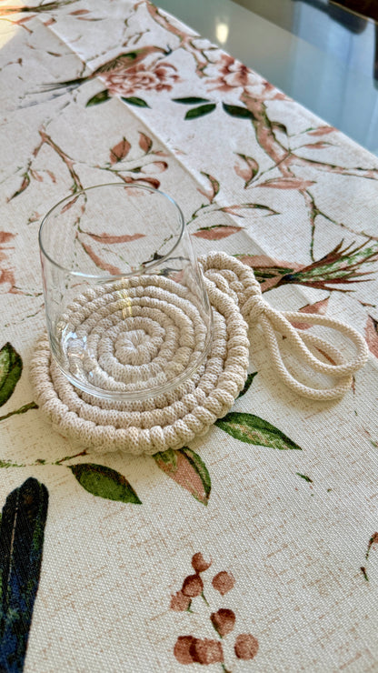 Beige woven coaster with a glass on a floral tablecloth