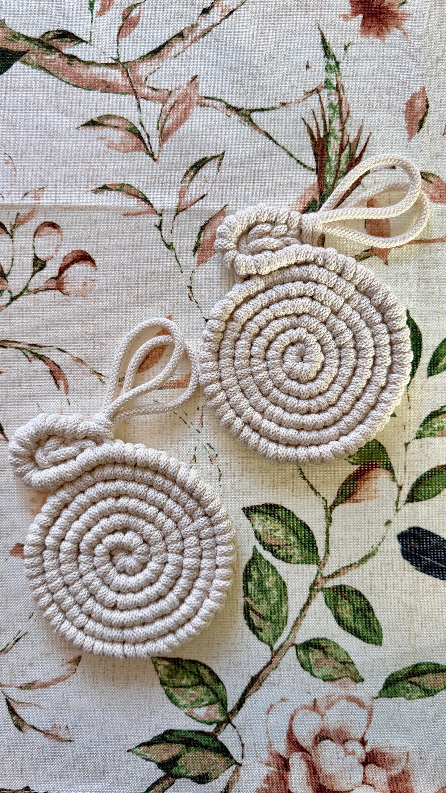 Two macrame easter bunny coasters on a floral fabric background