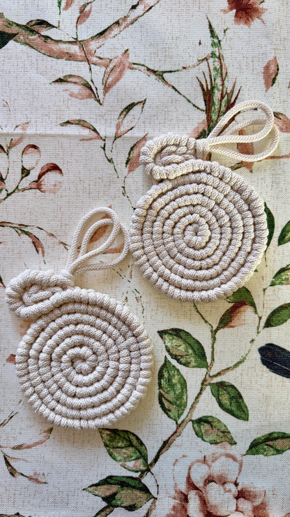 Two macrame easter bunny coasters on a floral fabric background
