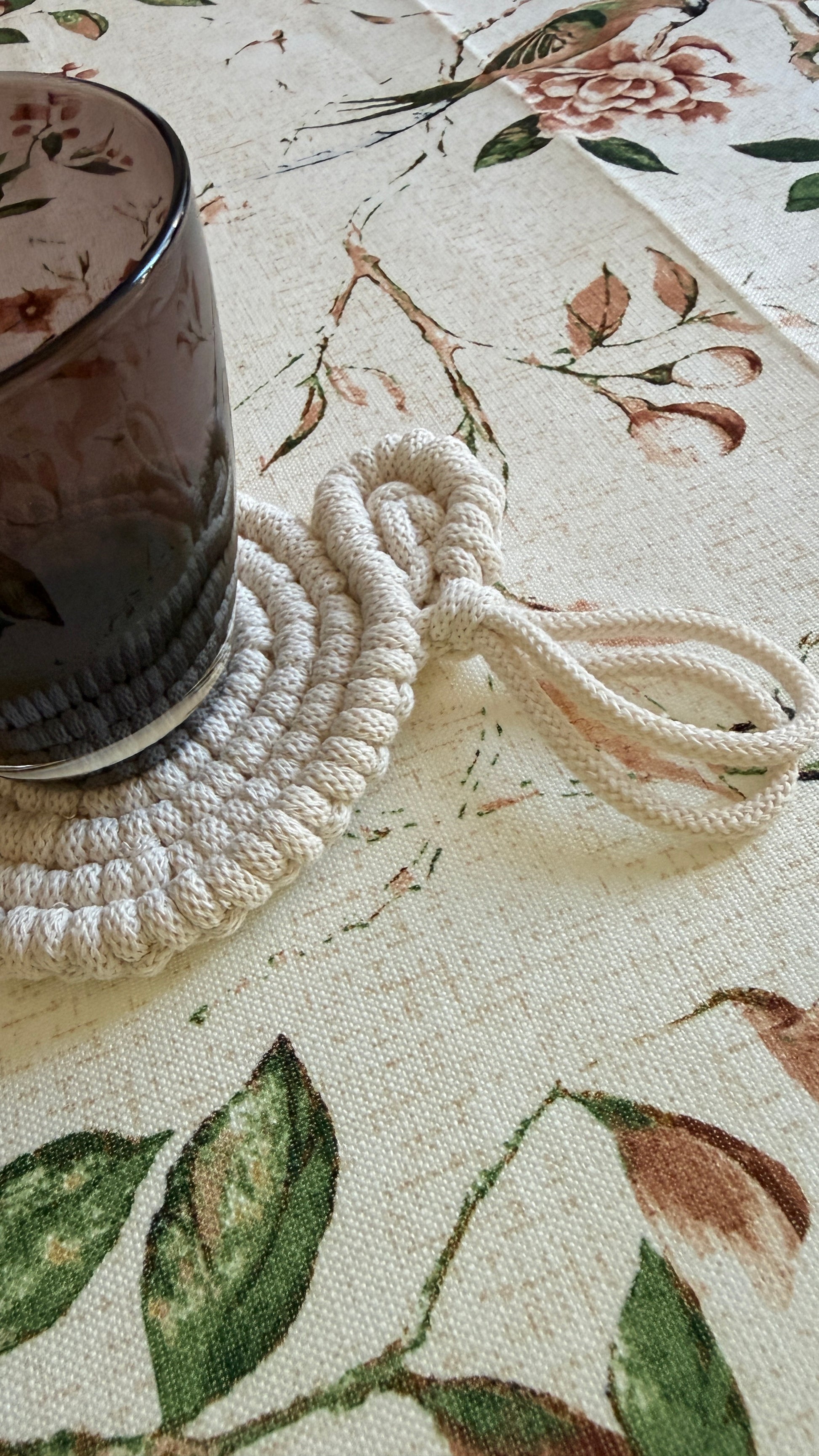 Macrame coaster with a glass on a floral-patterned surface
