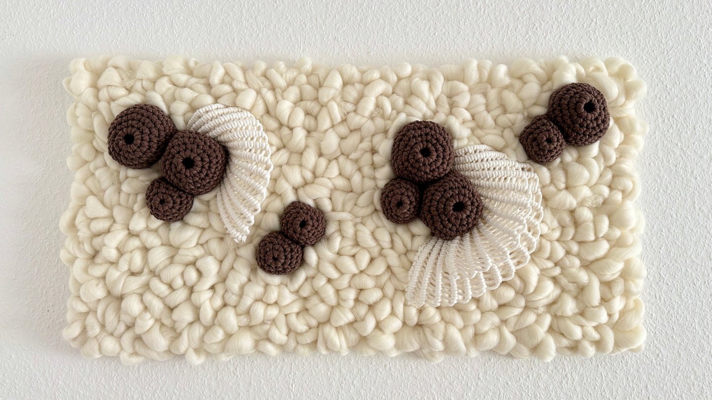 Textured white wall tapestry with brown crochet coral elements and white lace on a light gray background