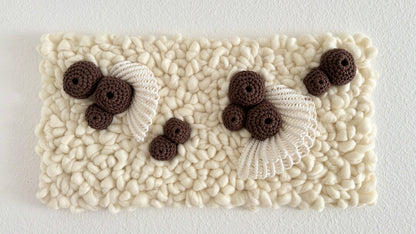 Textured white wall tapestry with brown crochet coral elements and white lace on a light gray background