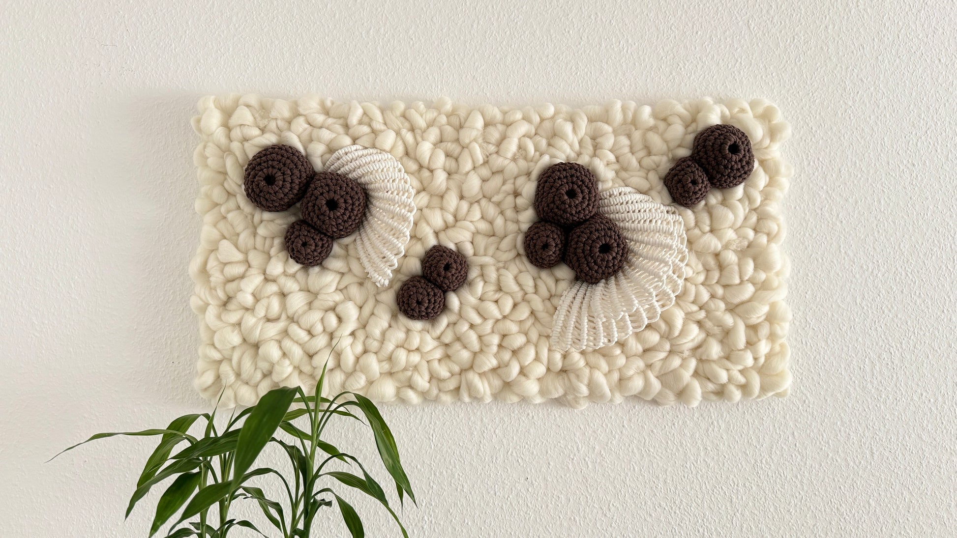 Decorative wall art with textured white surface and black and brown floral elements on a white background.