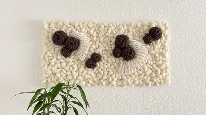 Decorative wall art with textured white surface and black and brown floral elements on a white background.