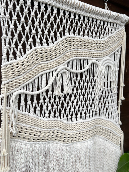 Close-up of a macrame wall hanging with intricate patterns and fringes.