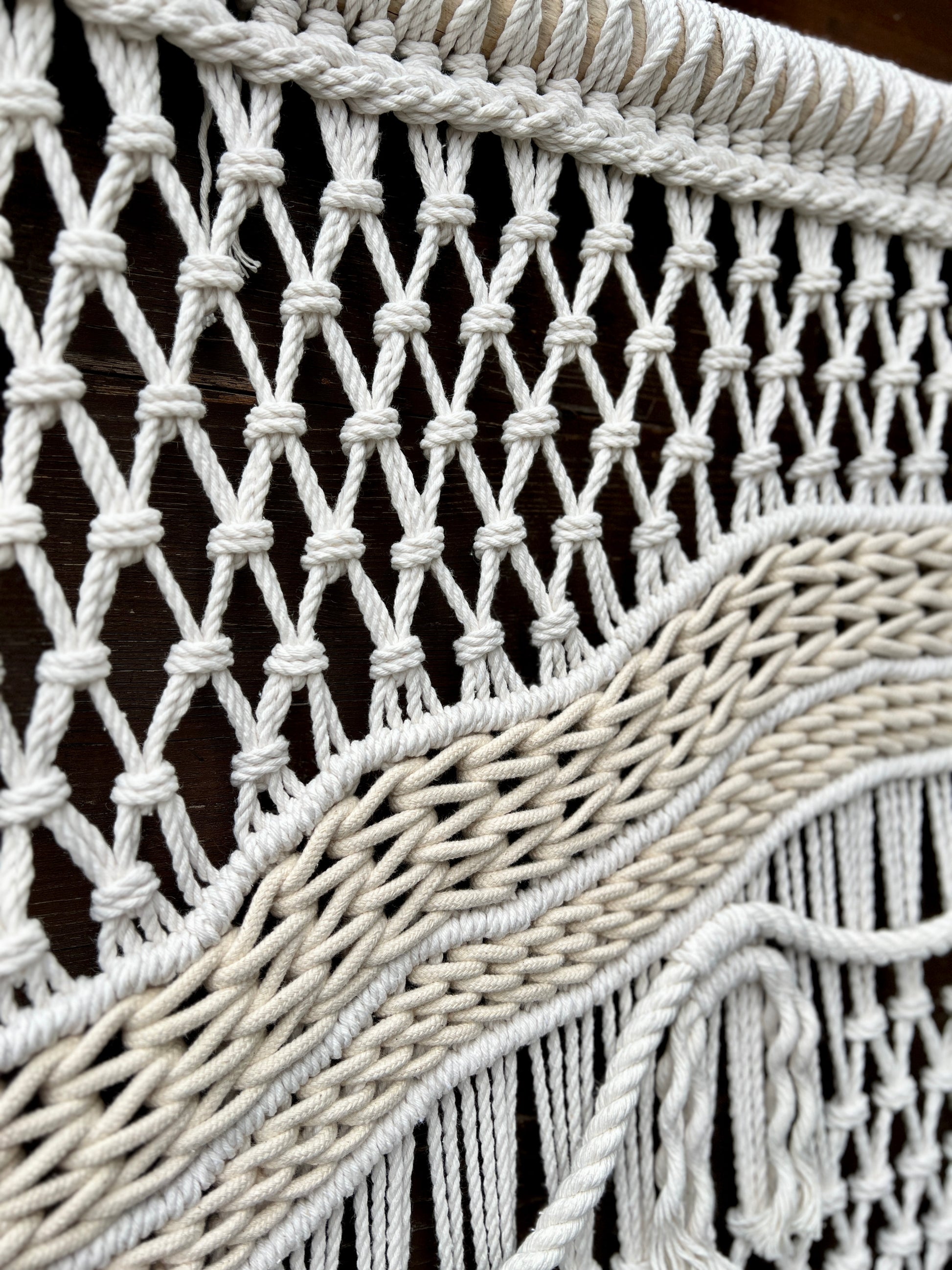 Close-up of a macrame wall hanging with intricate patterns and fringes.