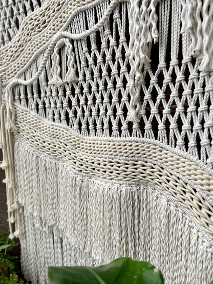 Close-up of a macrame wall hanging with intricate patterns and fringes.