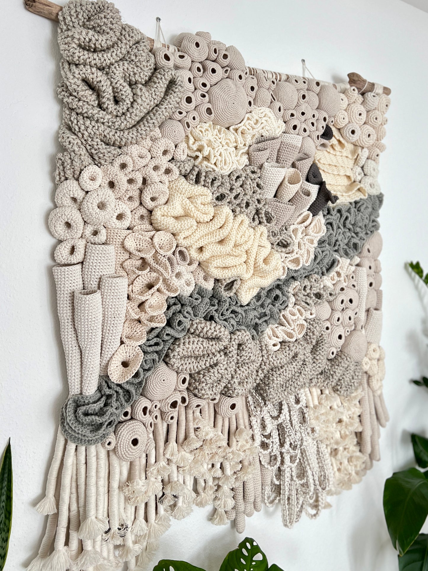 Textile art piece with crochet patterns on a white wall
