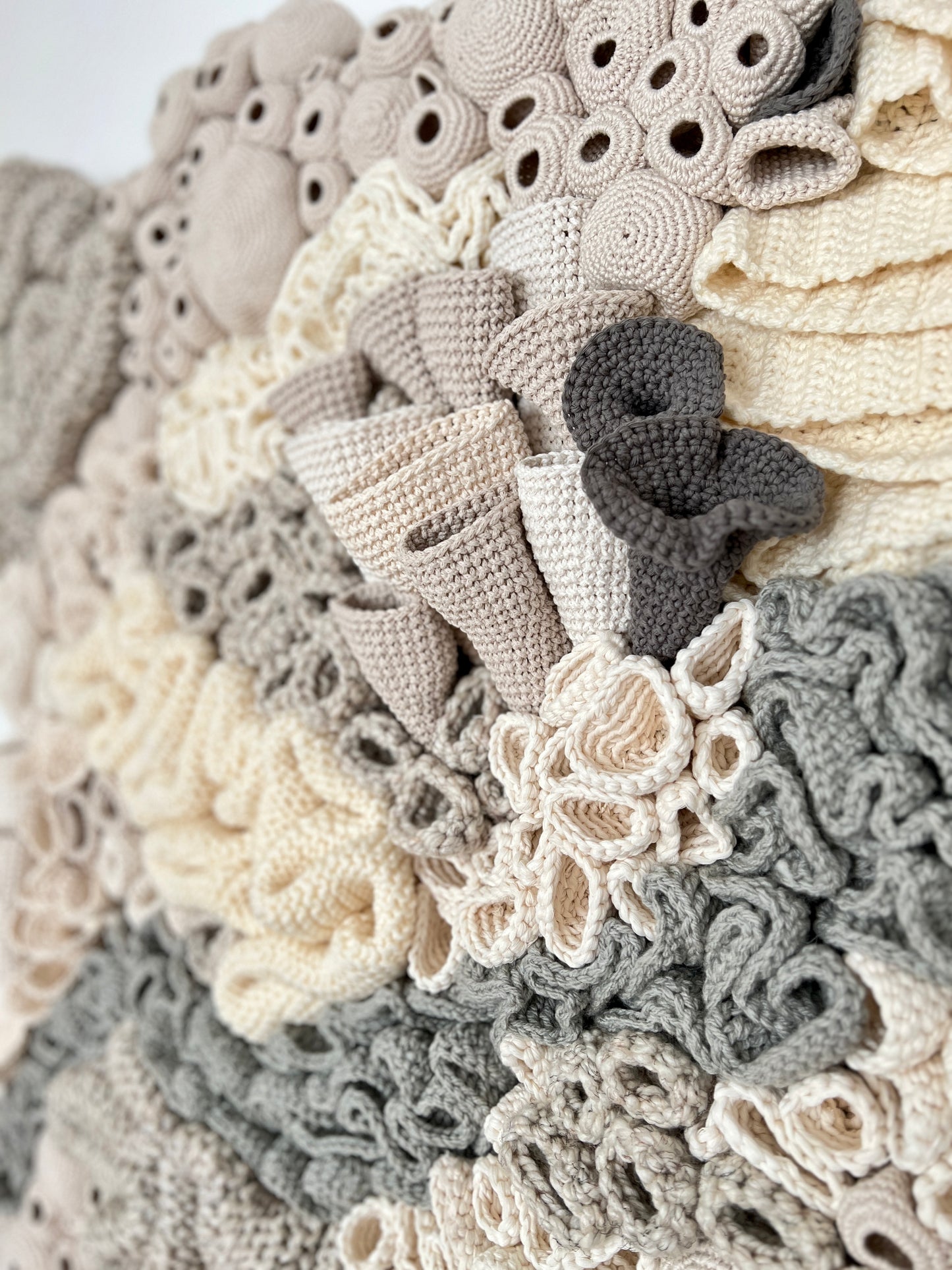 Close-up of a textured, crocheted coral reef details with textured accents  in neutral colors.