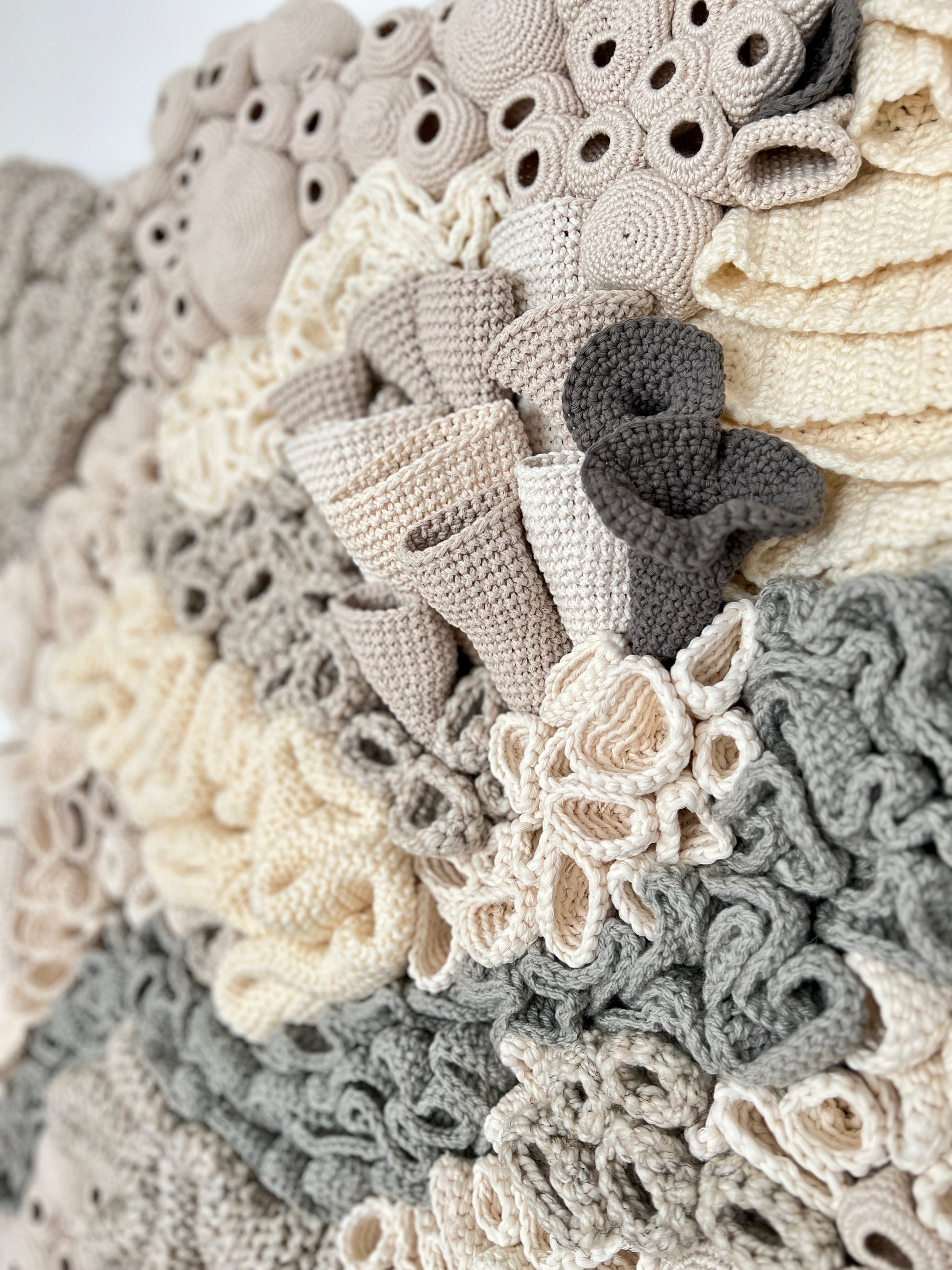 Close-up of a textured, crocheted coral reef details with textured accents  in neutral colors.