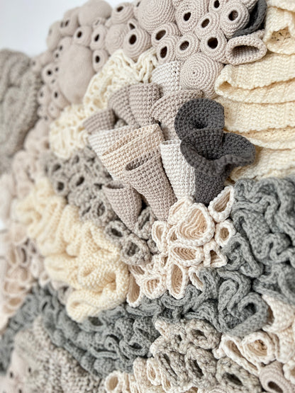 Close-up of a textured, crocheted coral reef details with textured accents  in neutral colors.