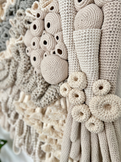 Close-up of a textured beige fabric with coral reef patterns and beads.