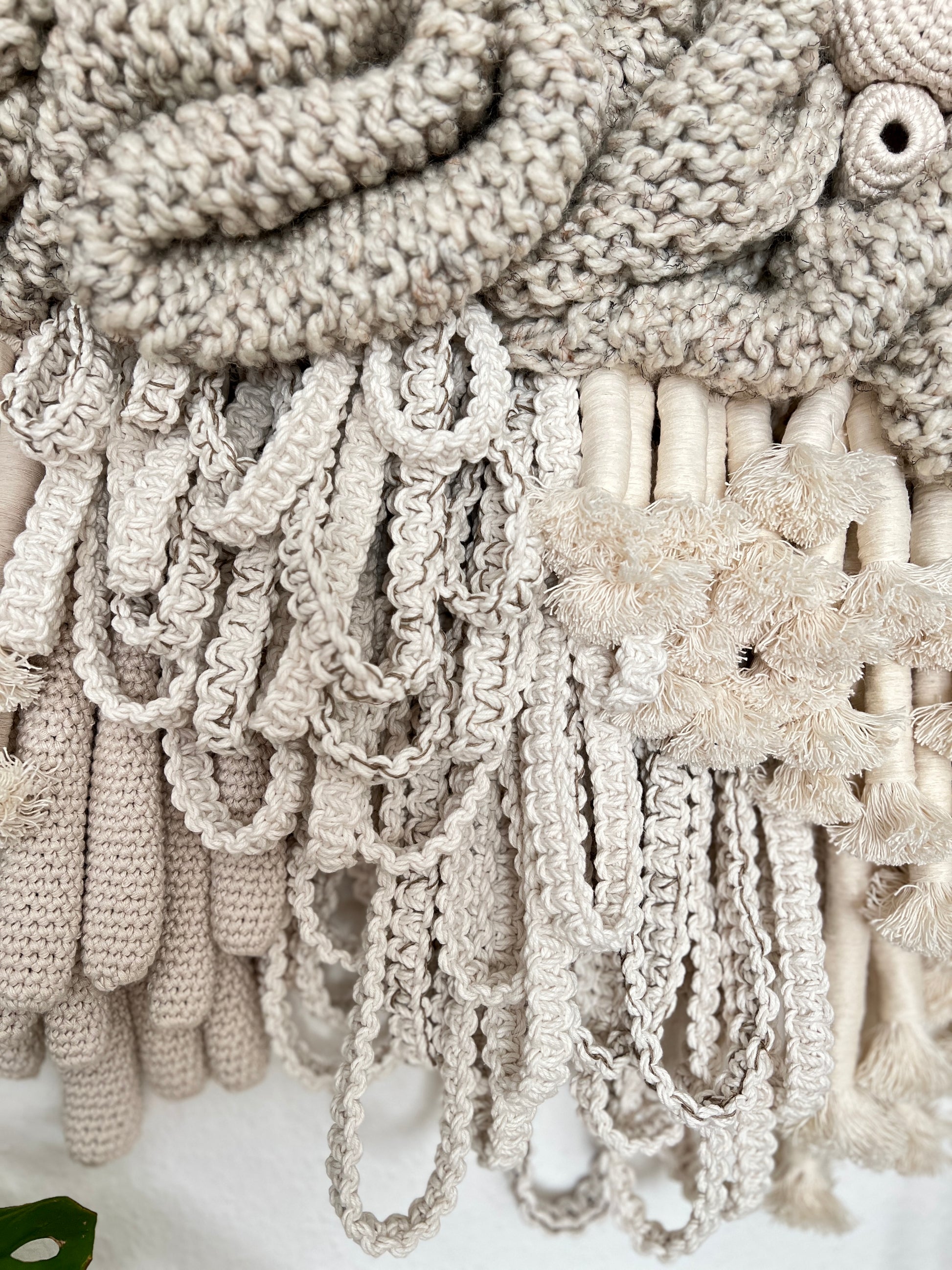 Close-up of textured beige fabric with fringes and a floral pattern.