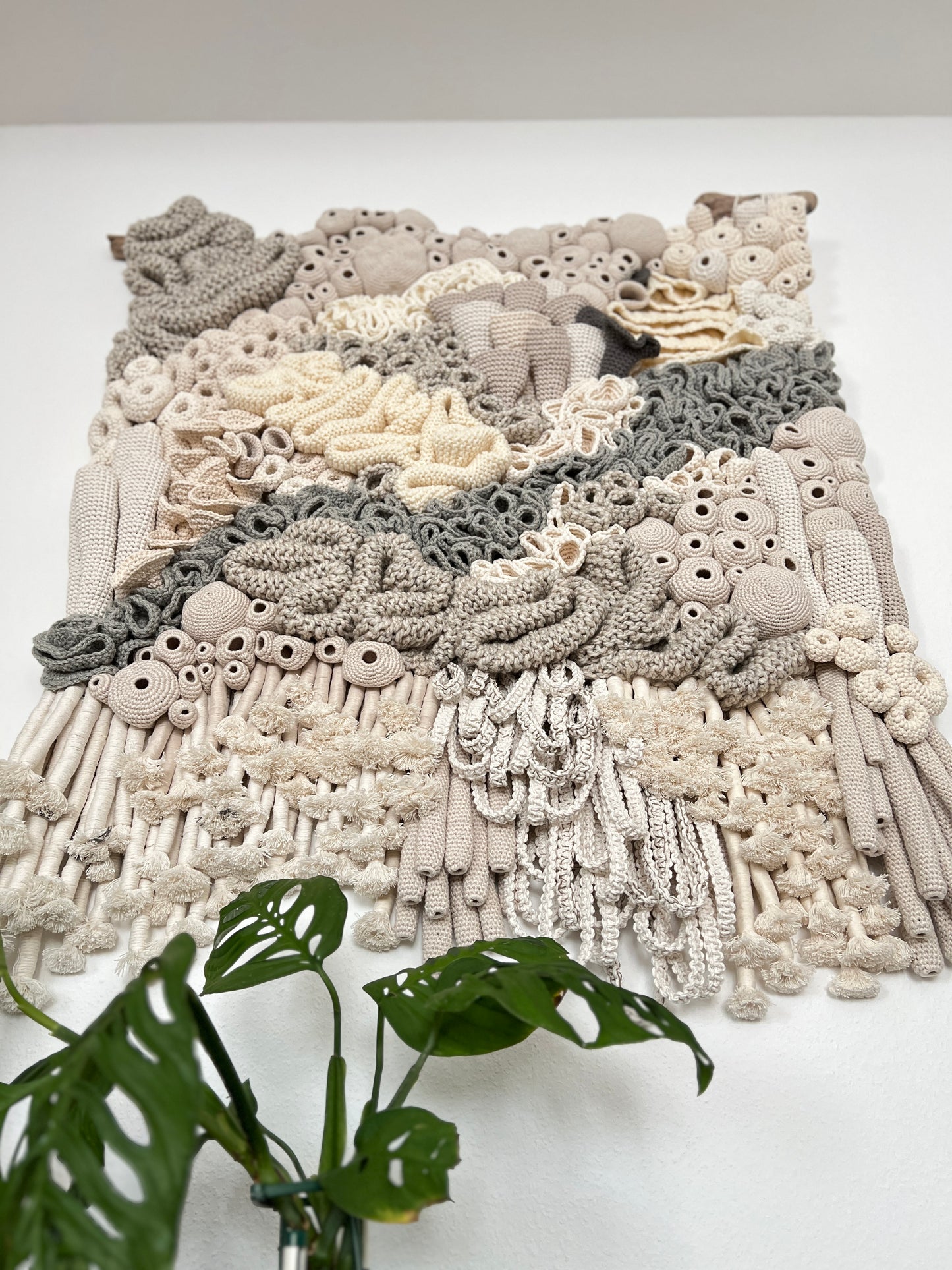 Textured wall art piece with a plant on a white background