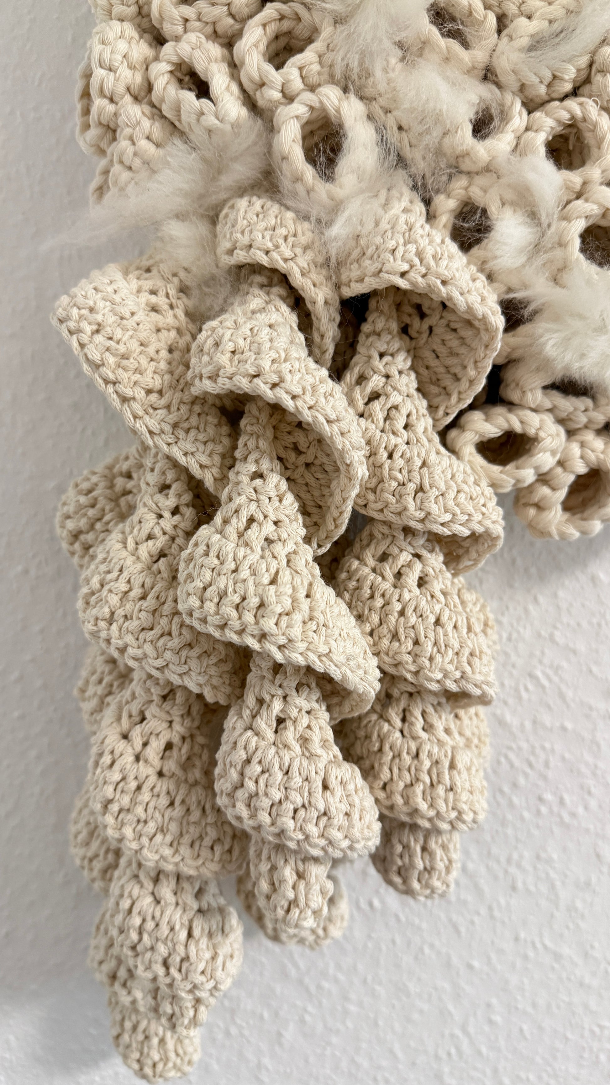 Textured beige crochet fabric on a textured white background