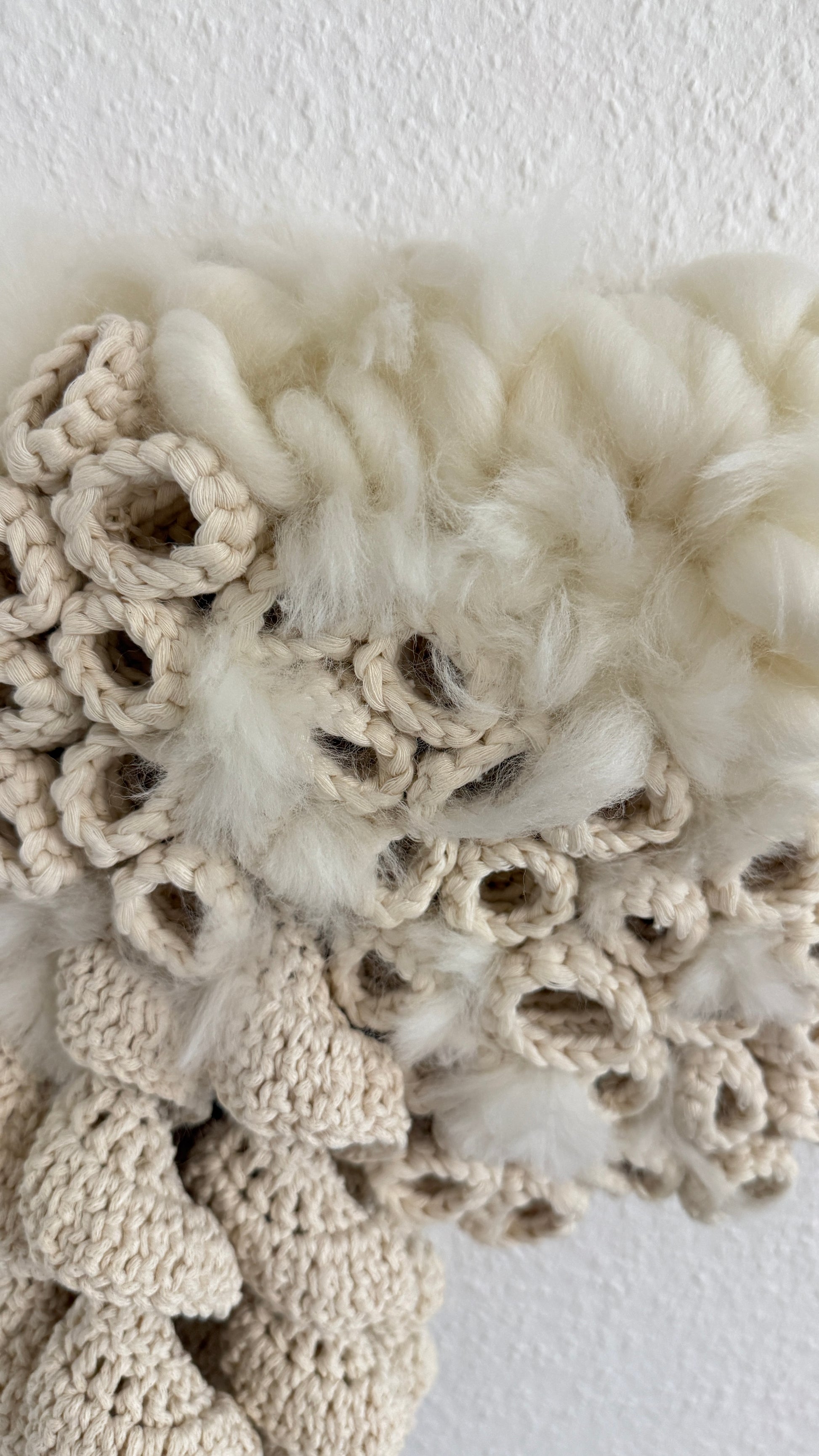 Textured beige and white wool with crochet pattern on a plain background
