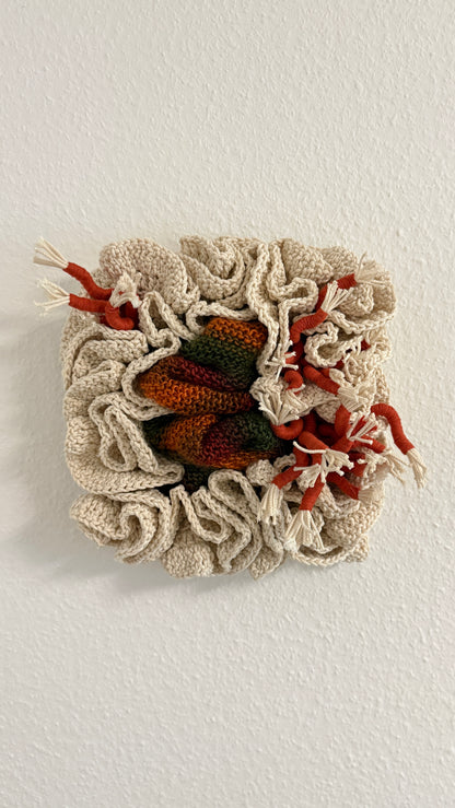 Textile art piece with a woven pattern and embroidered elements on a white background