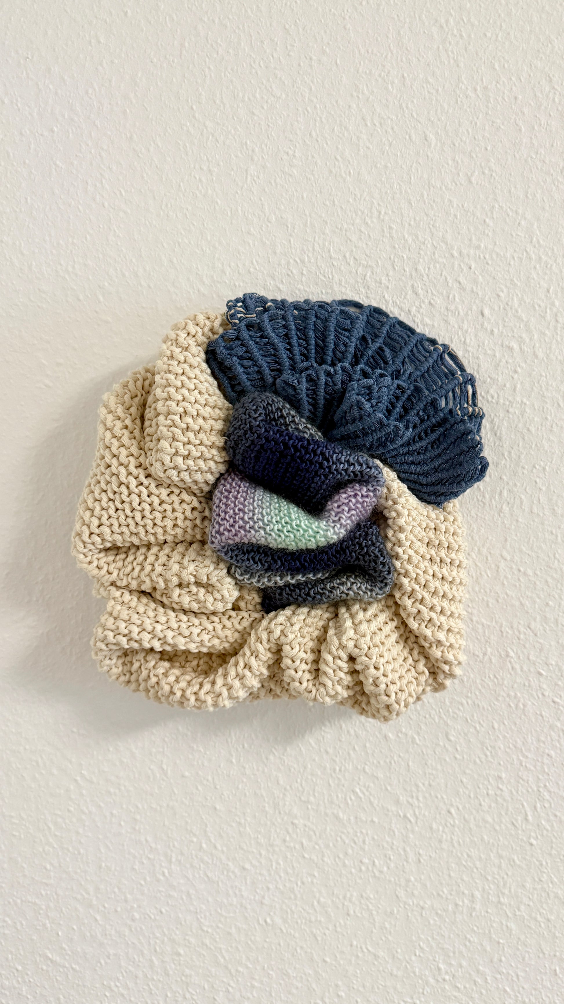 Knitted detail of wall hanging with a textured pattern on a light background