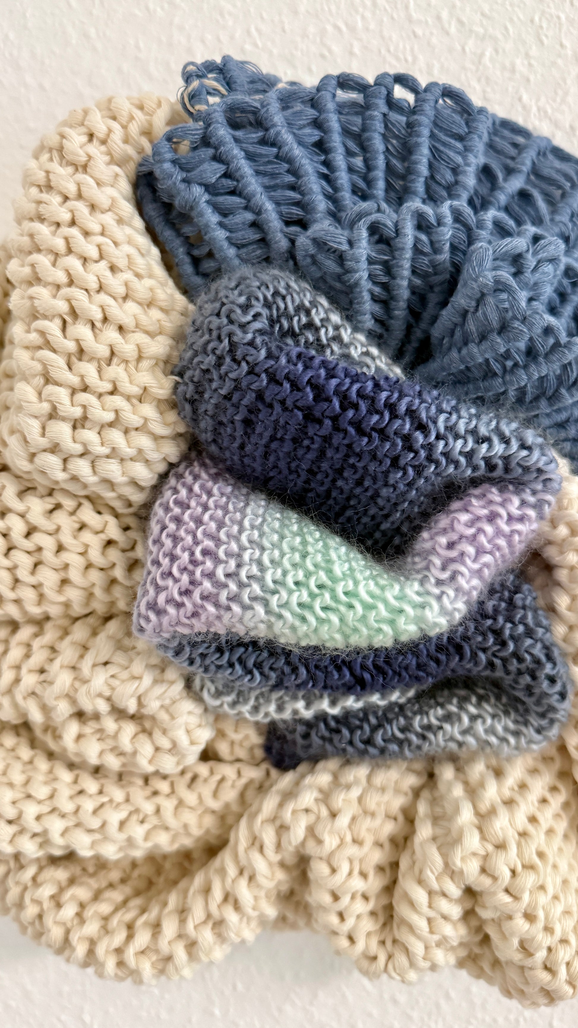 Stack of crocheted items in blue and gray on a textured beige surface