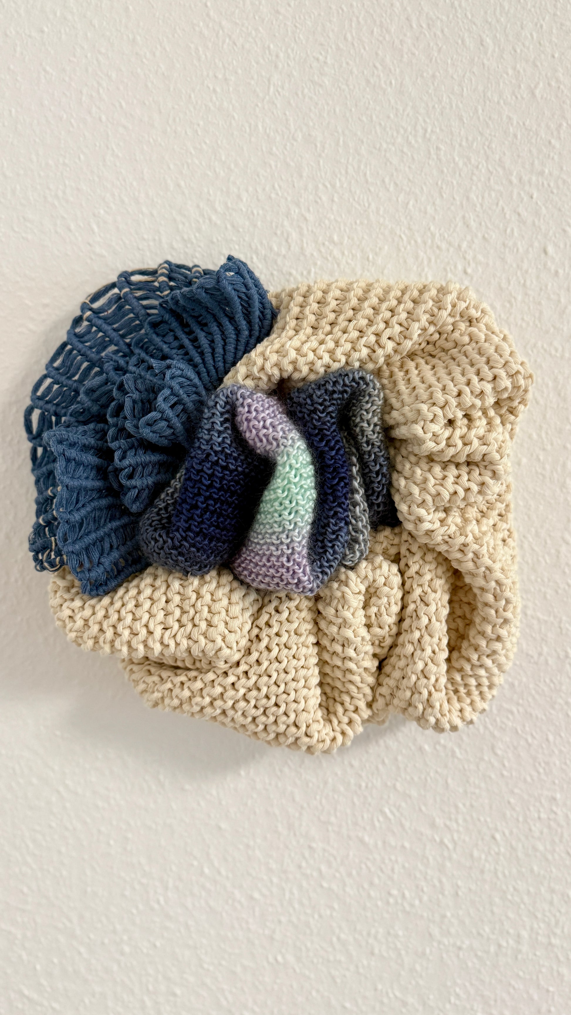 Knitted wall hanging with blue and purple gradient on a light background