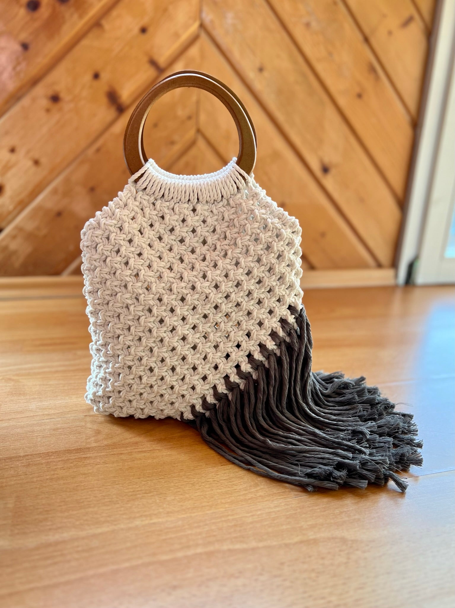 Macrame handbag with wooden handle on a wooden floor