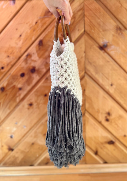 Handmade bag with white top and gray bottom held against a wooden background