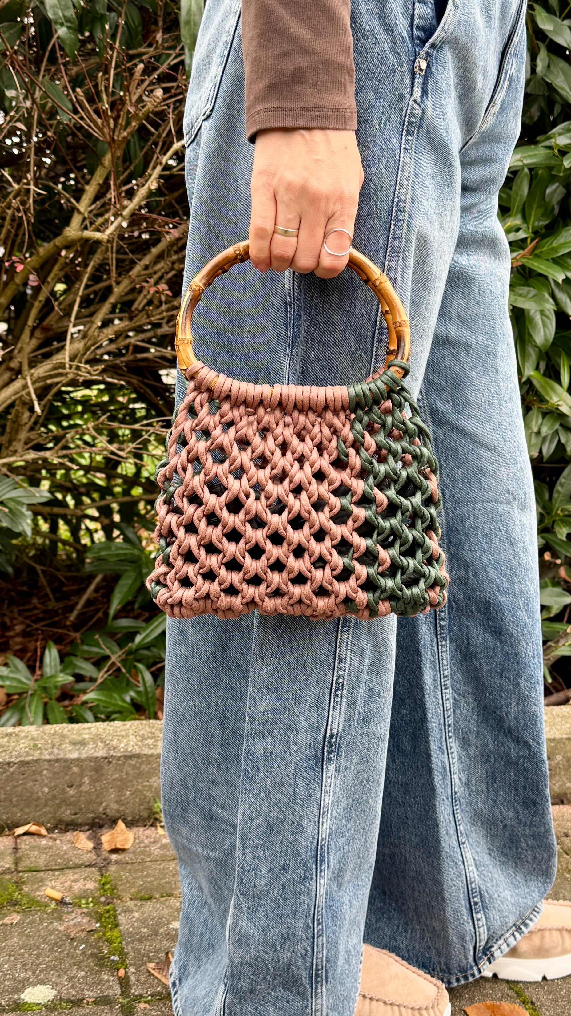 Person holding a woven macrame handbag with a blurred background